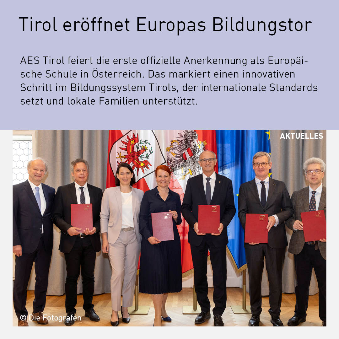 Offizielle Unterzeichnung in Tirol zur Anerkennung der AES Tirol als erste Europäische Schule Österreichs, mit Vertretern der Regierung und Bildungseinrichtungen vor den Tiroler und europäischen Flaggen.