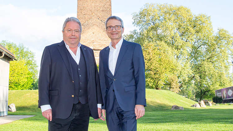 Franz Hörl und Erik Wolf, stehend auf der Wiese vor geziegeltem Turm, Österr. Seilbahntag Graz
