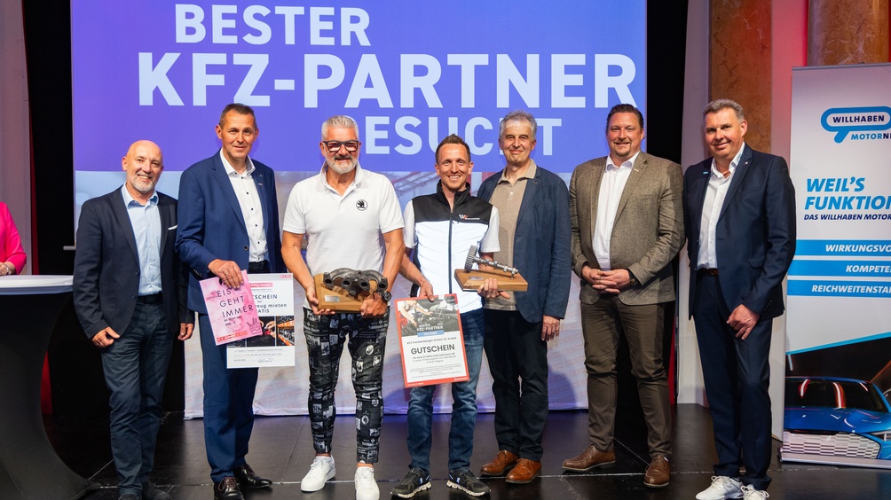 7 Männer auf Bühne posieren für das Foto