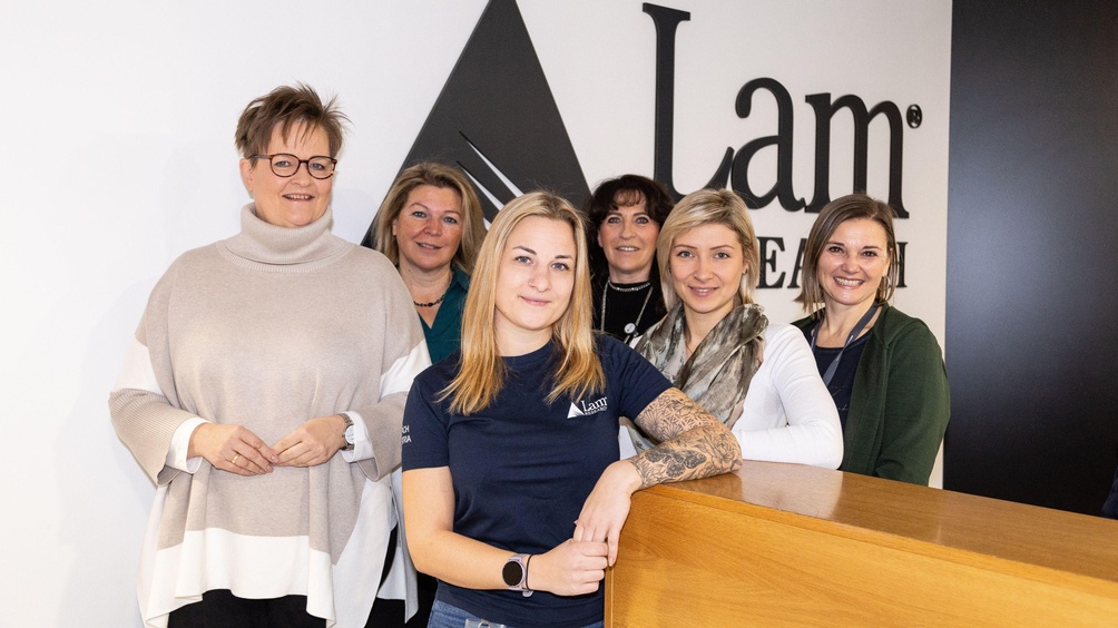 Eine Gruppe von Frauen vor einem Firmenlogo.