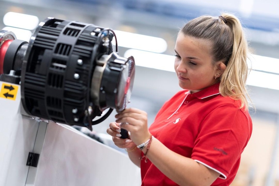 Frau in rotem Poloshirt arbeitet an der Maschine