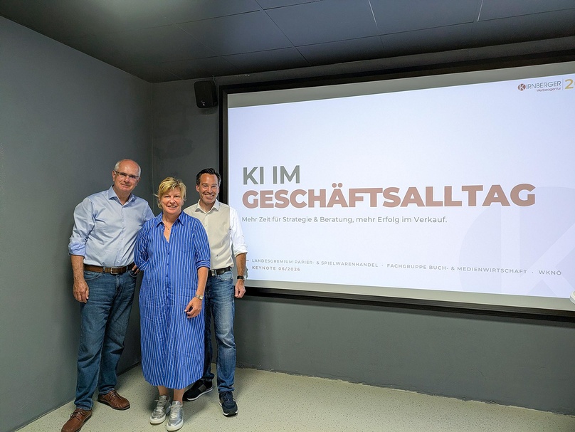 3 Personen vor Leinwand mit "KI im Geschäftsalltag"