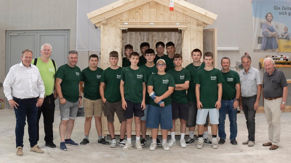 Die Absolventin und die Absolventen der ersten „Lehrlingswoche“ des NÖ Holzbau-Nachwuchses vor dem von ihnen gezimmerten Verkaufsstand und flankiert von zahlreichen Gratulanten: Jochen Flicker (Spartenobmann NÖ Gewerbe und Handwerk), Wolfgang Huber (Landesinnungsmeister NÖ Holzbau) und „Lehrlingswoche“-Trainer Harald Forstenlechner (im Bild links, v.l.n.r.) sowie Franz Schrimpl (Obmann proHolz NÖ), Andreas Mokesch (BAUAkademie NÖ Schloss Haindorf) und „Lehrlingswoche“-Trainer Rudolf Schneider (im Bild rechts, v.r.n.l.).