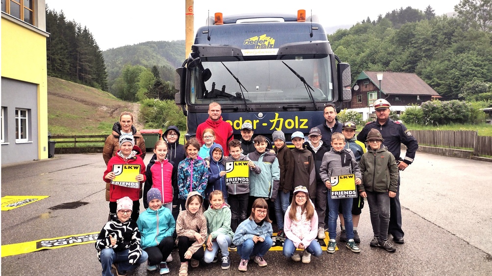 Schulbesuch - Gruppenbild mit den Schülern, Lehrerin, Polizist, LKW-Fahrer und LKW: