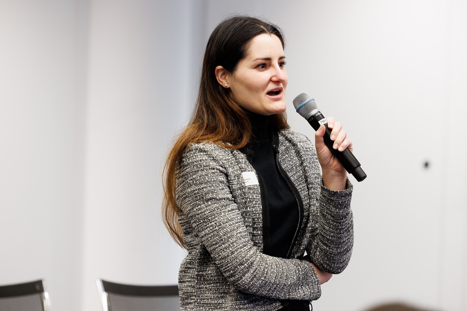 Person in Seitenansicht spricht in Mikrofon und hält einen Arm vor Oberkörper verschränkt