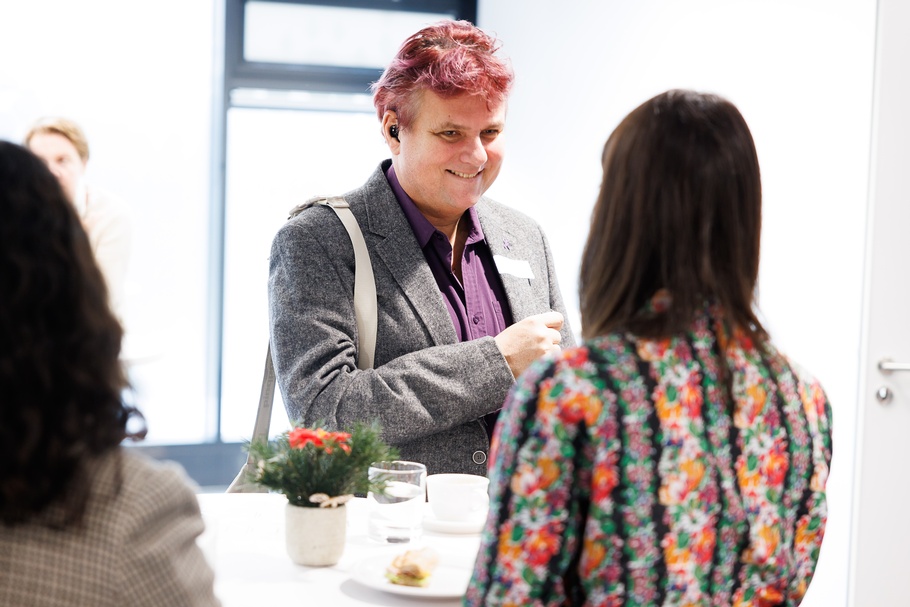 Fokus auf lächelnde Person, die mit anderer Person in Rückenansicht an Stehtisch steht