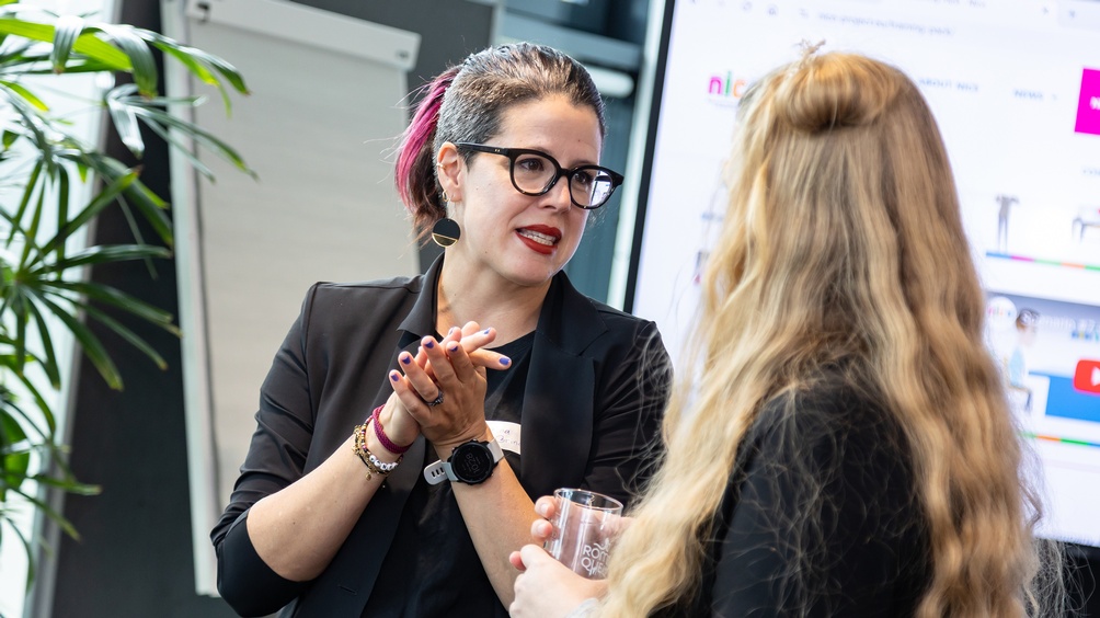 Zwei Personen im Gespräch miteinander, Fokus auf sprechende Person, die andere in Rückenansicht