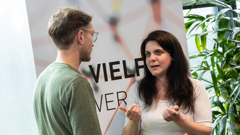 Zwei Personen im Gespräch miteinander, Fokus auf sprechende Person, die andere in Rückenansicht