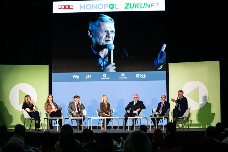 Podiumsrunde auf der Bühne unter dem Schriftzug „MONOPOL ZUKUNFT“ und dem WKÖ Logo.