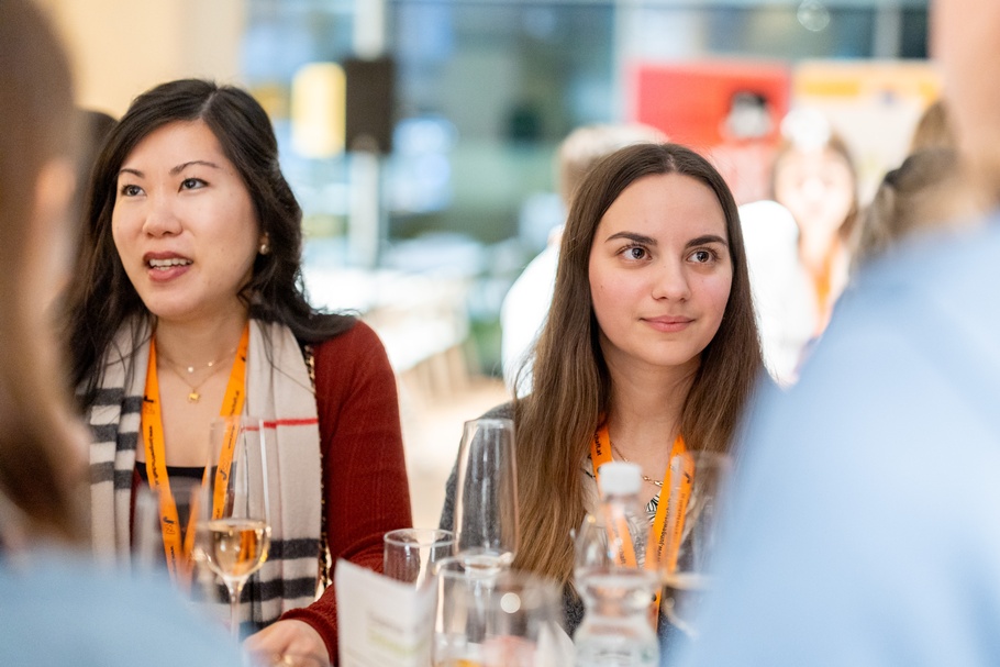 Zu sehen sind Personen, die an einem Tisch stehen, auf dem auch Gläser mit Sekt platziert sind.