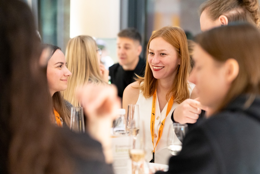 Over the shoulder-Shot von Menschen, eine Person ist im Fokus, bei anderen sind nur Silhouetten erkennbar.