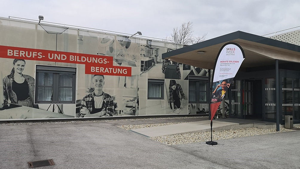 Eingangsbereich mit Fahne und großem Plakat zur Skills Week Austria