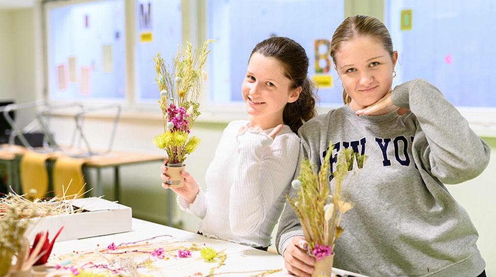 Zwei lächelnde Kinder mit Blumensträußchen in Händen posieren für die Kamera