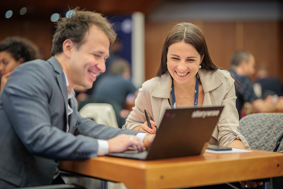 Zwei lächelnde Personen vor einem Laptop am Connect Day
