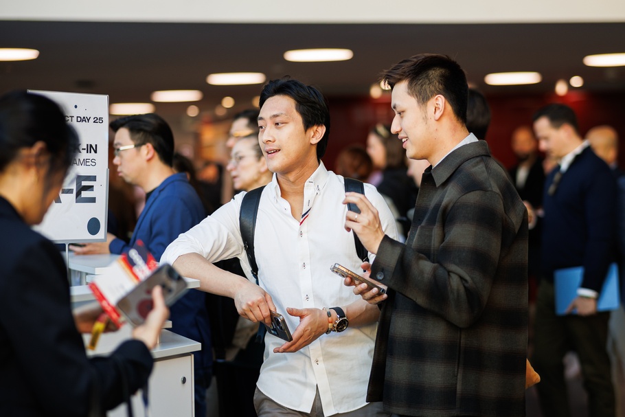 Fokus auf zwei Personen in einer Menschenmasse, die am Check-In-Schalter eines Events miteinander sprechen