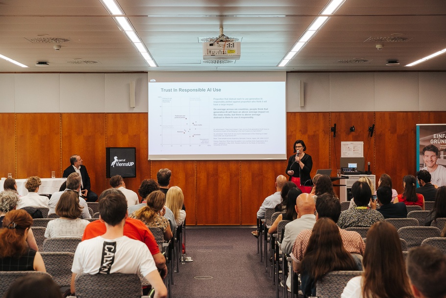 Vortragssaal mit Besucher:innen und einer Vortragenden am Mikrofon 