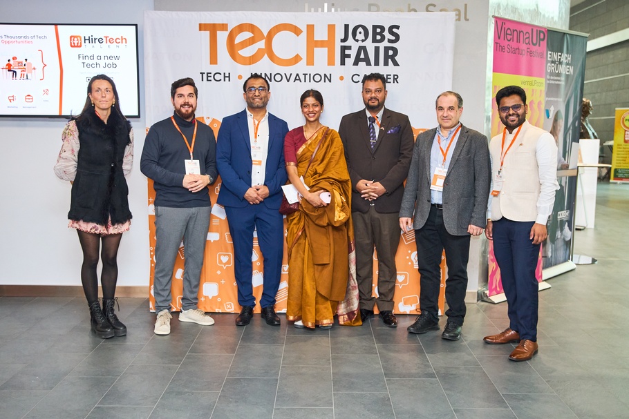 Personen stehen nebeneinander, hinter ihnen ist ein Roll-up mit dem Schriftzug Tech Fair