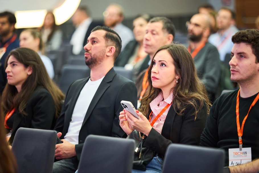 Nahaufnahme von Personen, die nebeneinander auf Sesseln sitzen. Eine Person hält ein Smartphone in der Hand