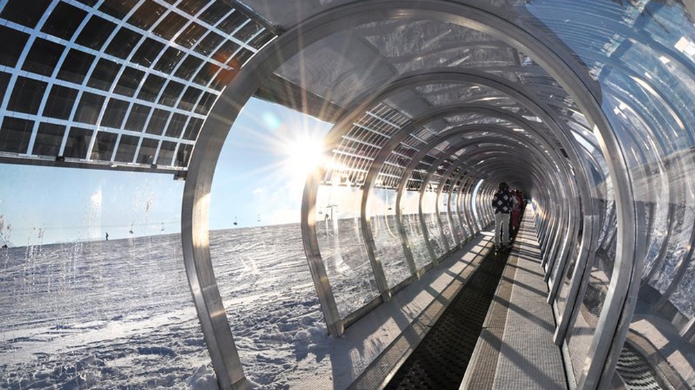 Ein gläserner Gang durch eine Schneelandschaft und Menschen