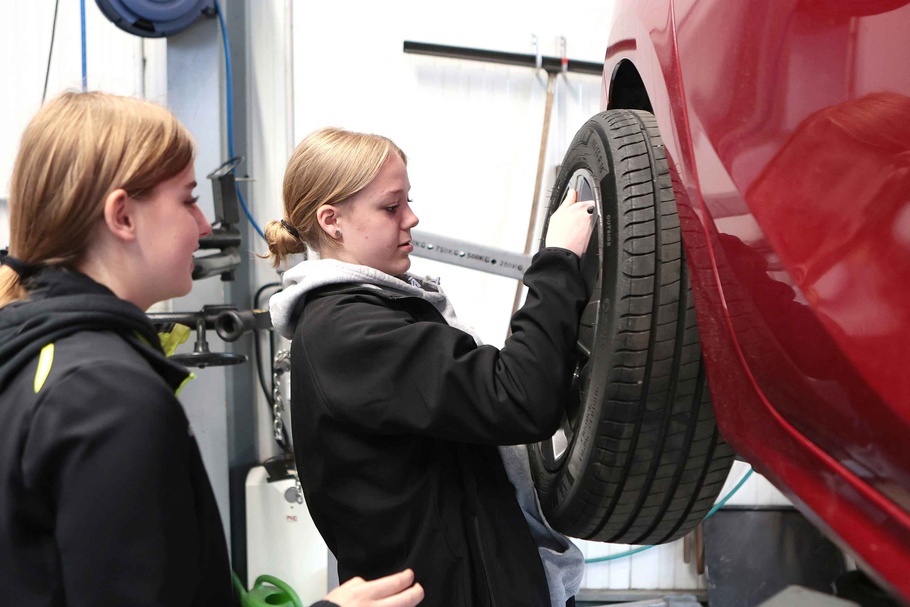Mädchen wechseln Reifen bei einem Auto.