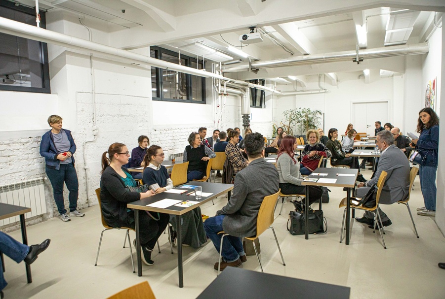 Eine Gruppe von Erwachsenen sitzt an Schreibtischen und führt Gespräche