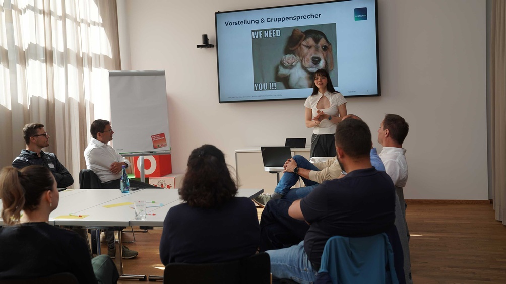 Man sieht mehrere Menschen in einem Seminarraum