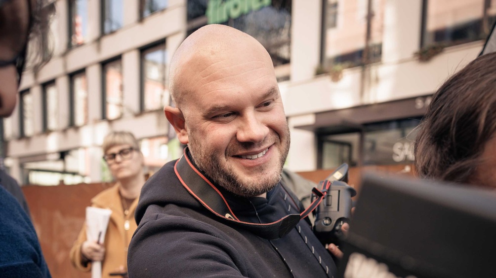 Man sieht den Fotografen Freddy Billqvist mit einer Kamera in der Hand, um ihn herum stehen mehrere Menschen