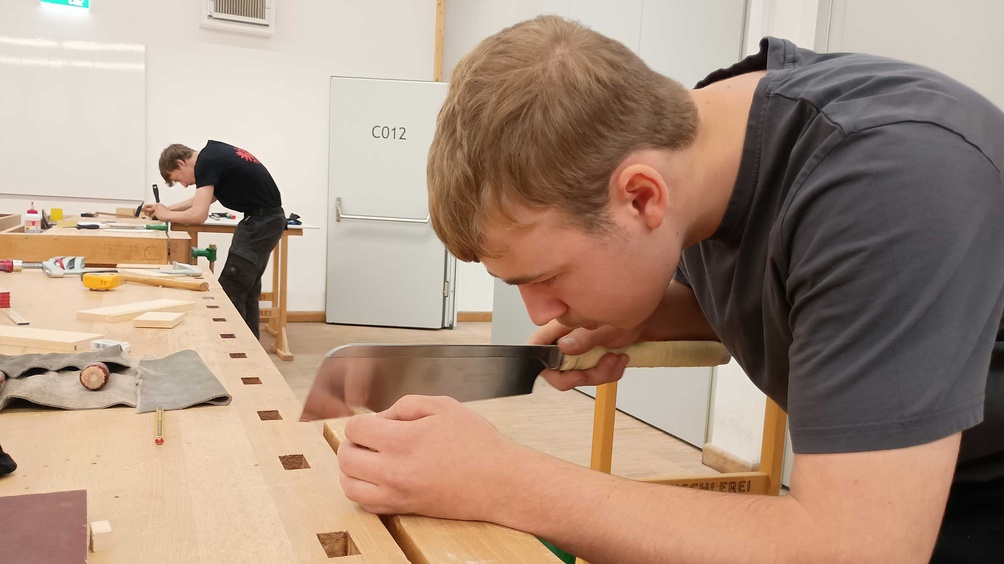 Zwei Jugendliche arbeiten konzentriert an ihren Werkstücken aus Holz
