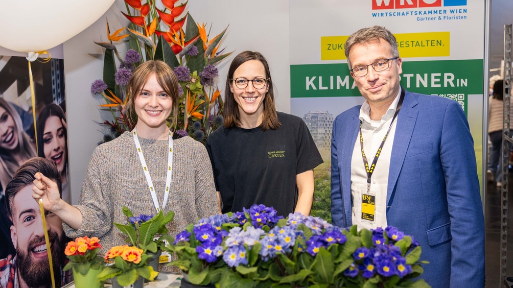 Drei Personen und Blumen im Vordergrund