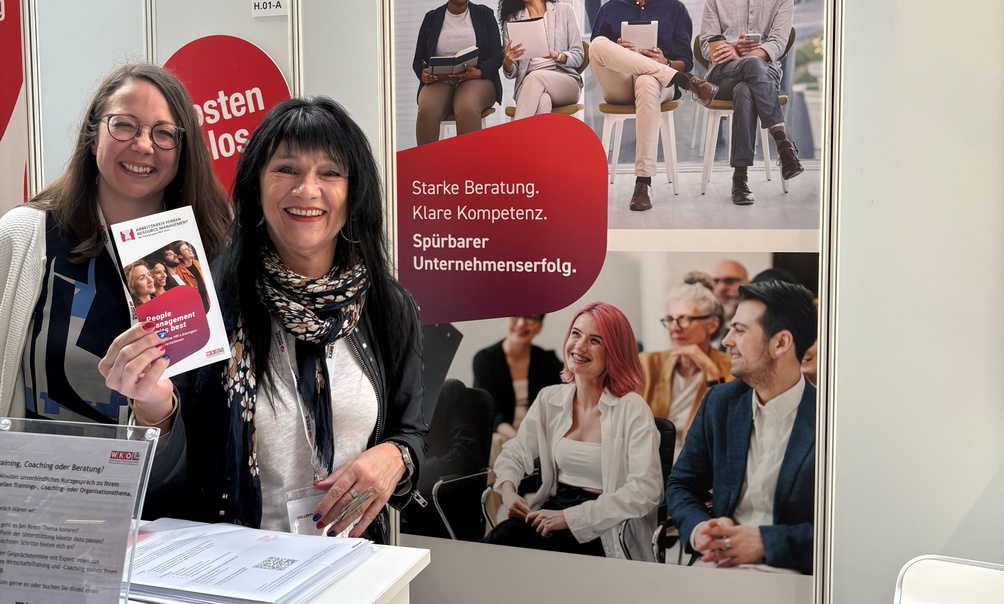 Zwei Personen bei einem Messestand