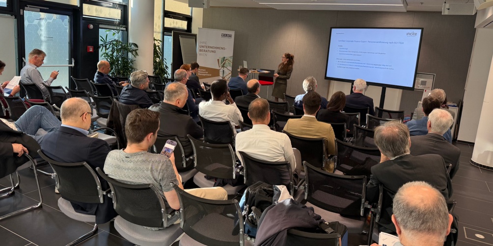 Personen sitzen während einer Veranstaltung im Publikum und hören zu.