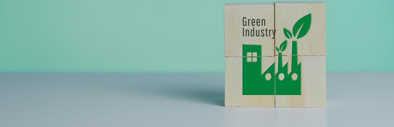 Auf Holzwürfeln ist eine grüne Fabrik aufgezeichnet. Daneben steht Green Industry