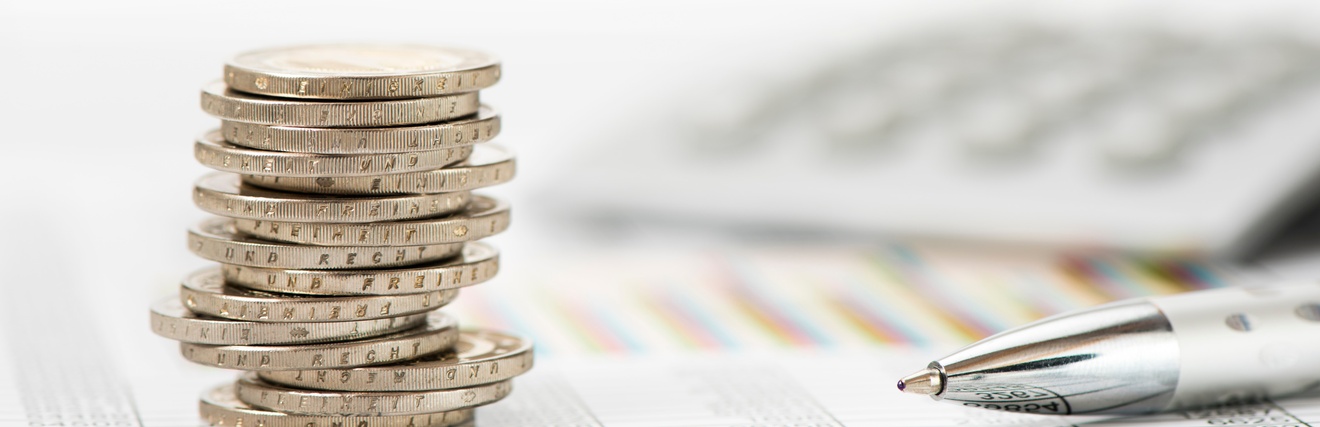 Stapel Münzen auf Dokumenten liegend daneben Kugelschreiber