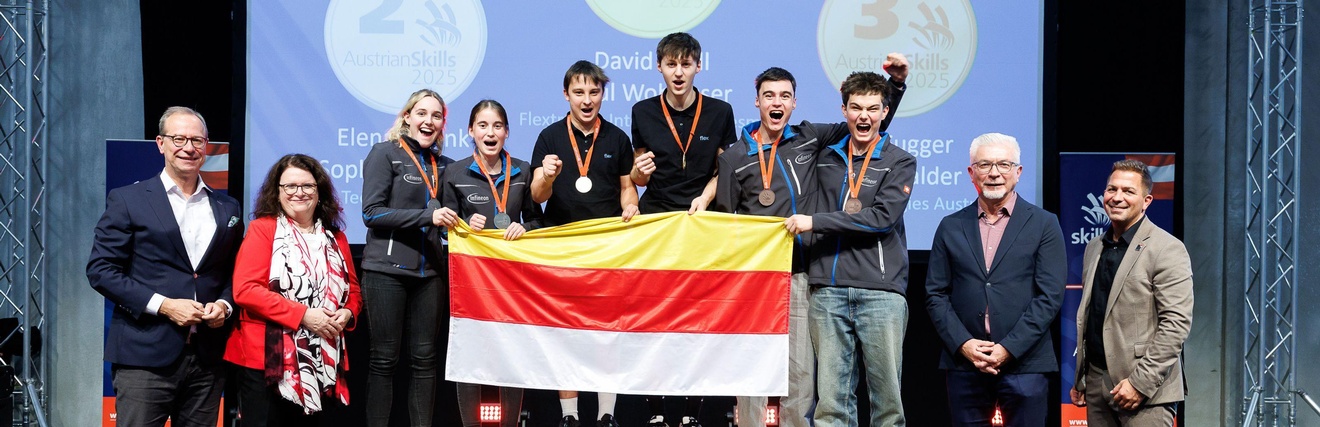 Die ersten drei Plätze in Mechatronik gehen nach Kärnten. Das Bild zeigt die Sieger auf dem Podest. Sie halten gemeinsam eine Kärnten-Fahne