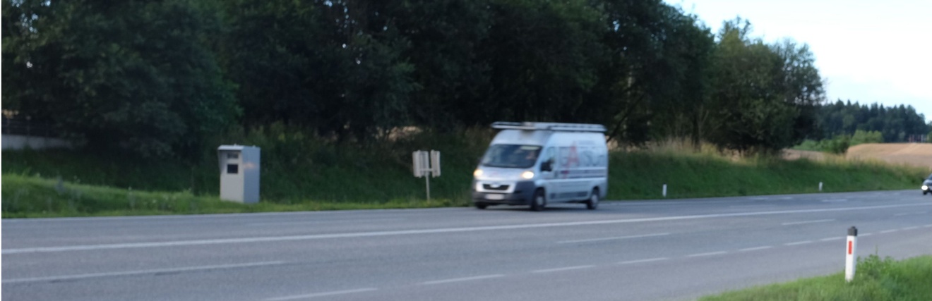 Vierspurige Straße mit einem Auto mit Bäumen im Hintergrund