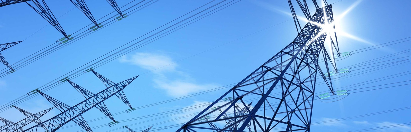 Hochspannungs-Stromleitung vor blauem Himmel.