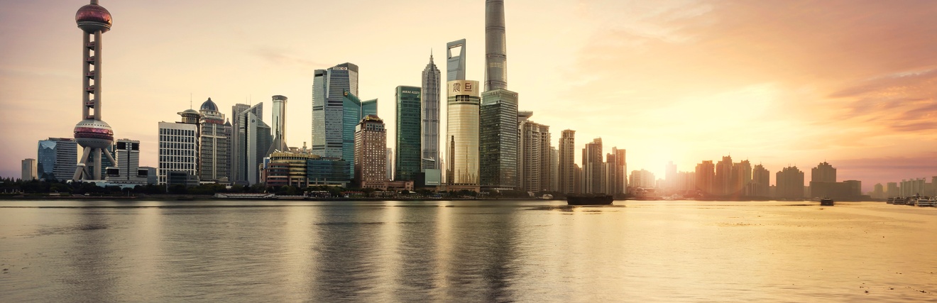 Stadtansicht Shanghai: Wolkenkratzer am Wasser gelegen im Sonnenuntergang