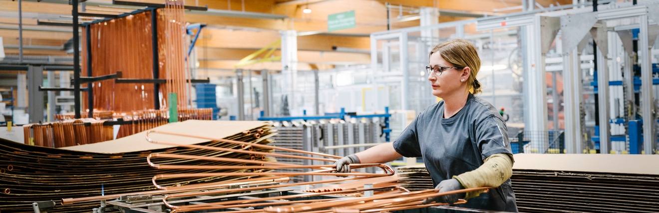 Person mit Brillen in Werkhalle stehend sortiert Solarpaneelleitungen