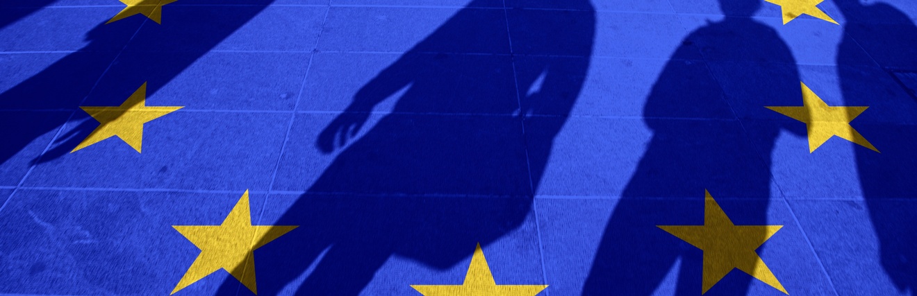 Blauer Boden mit im Kreis verlaufenden gelben Sterne, die Flagge der Europäischen Union symbolisierend, Schattenumrisse von vier Personen erkennbar