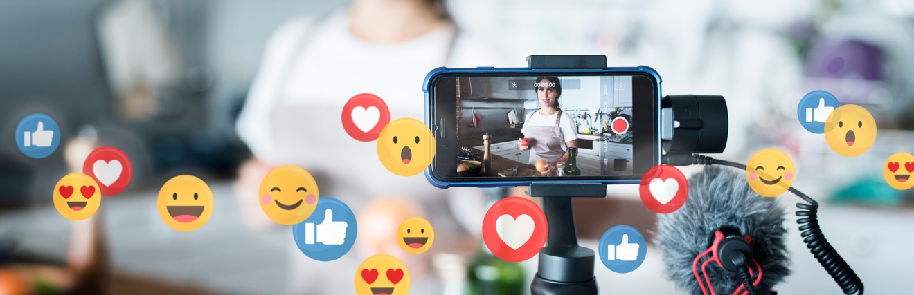 Person steht vor einem Set und nimmt die Situation mit einem Smartphone auf einem Stativ mit Mikrofon live für Social Media auf