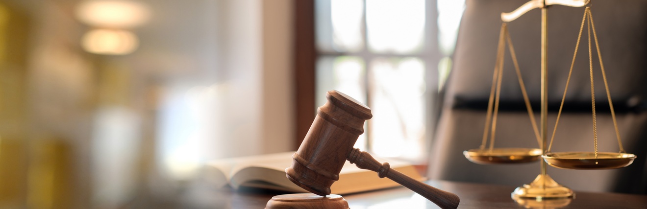 Ein Richterhammer neben einer Waage auf einem Tisch.