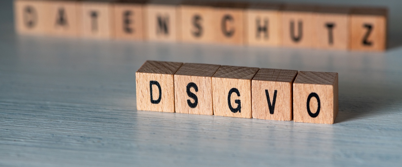 Buchstaben formen DSGVO im Fokus, im Hintergrund steht der Schriftzug Datenschutz