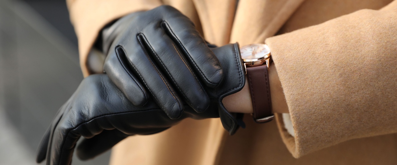 Schwarze Lederhandschuhe und eine Armbanduhr mit einem braunen Lederarmband