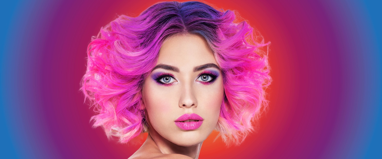 Frau stark pink und lila geschminktmit pinken Haaren und Locken.