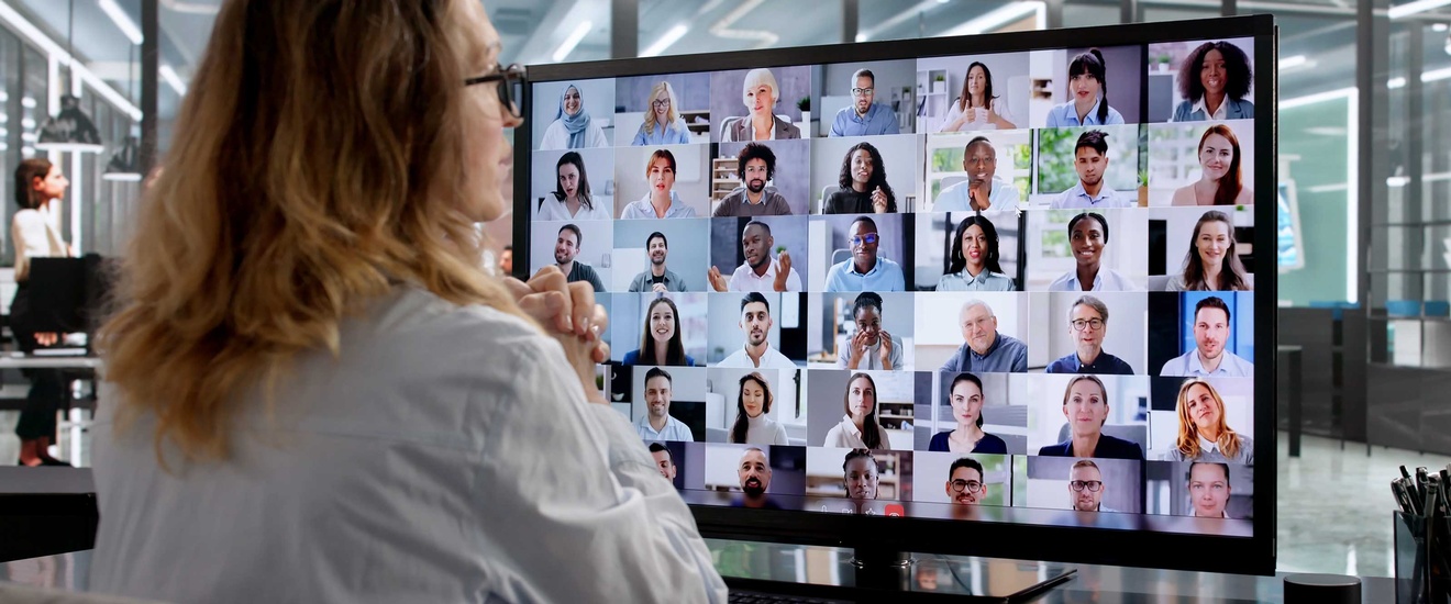 Eine Person sitzt an einem Schreibtisch vor einem Bildschirm 