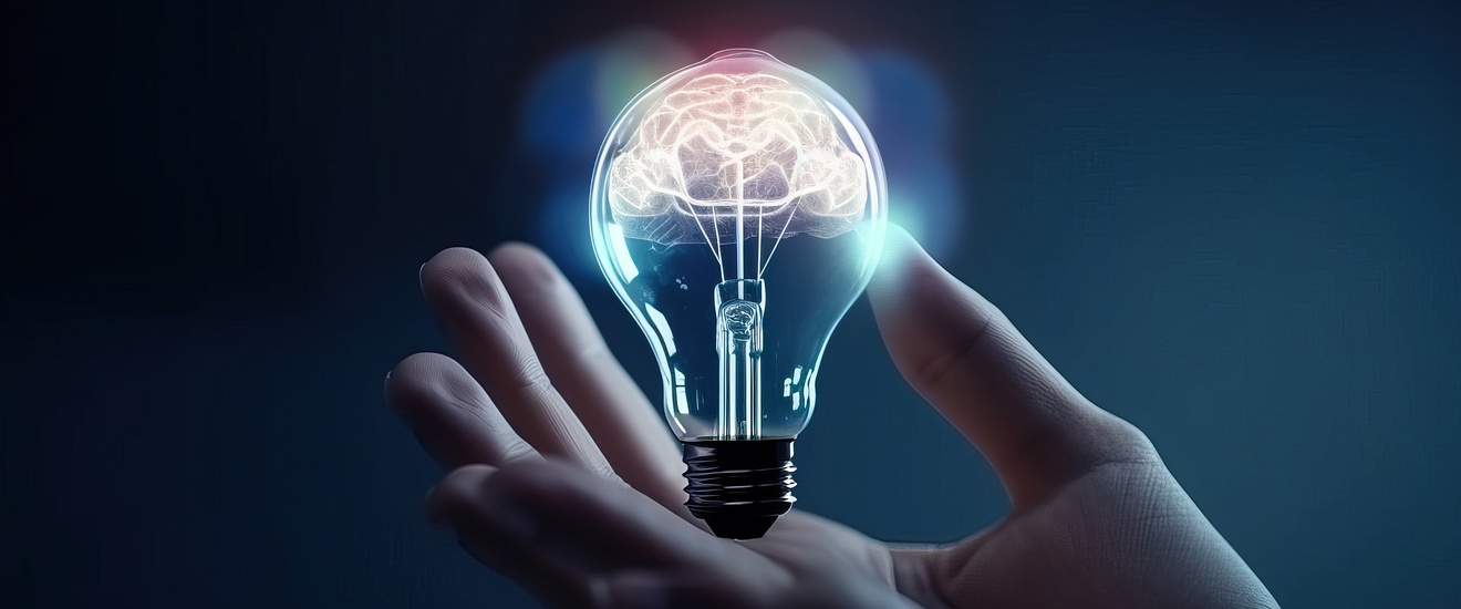 Eine Hand hält eine Glühbirne mit einem leuchtenden Gehirn darinnen
