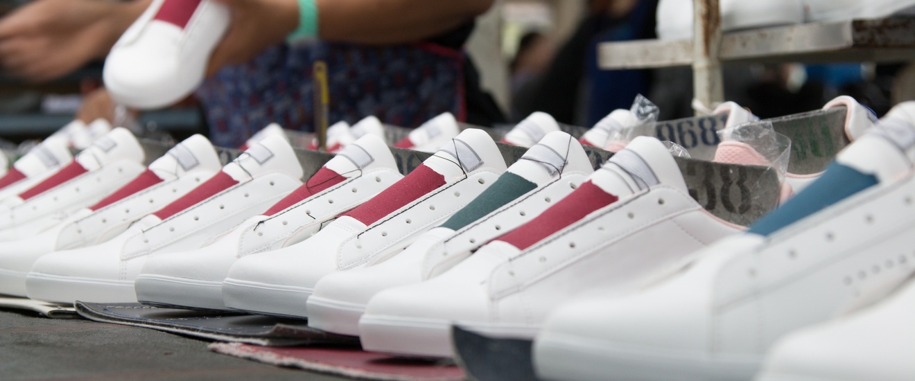 Detailansicht mehrerer weißer Sneaker mit farblichen Elementen in der Herstellung