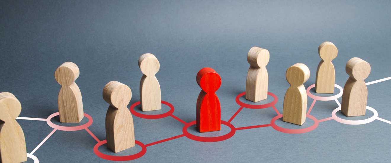 Konzept Teamwork und Zusammenarbeit in einem Netzwerk bestehend aus Holzfiguren und einer rot gefärbten Figur