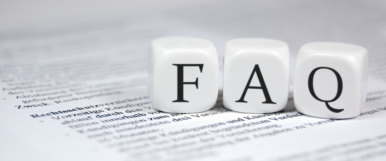 Drei weiße Würfel liegen nebeneinander auf einem bedruckten Papier. Auf dem linken Würfel ist ein f, dann folgt ein a und dann ein q