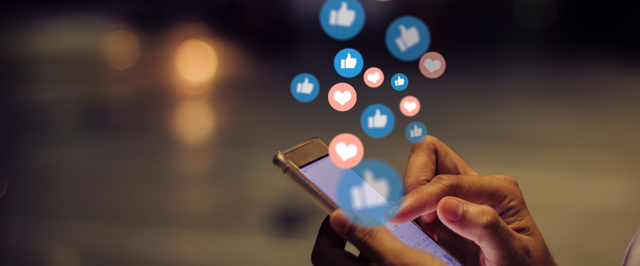 Seitliche Nahaufnahme zweier Hände einer Person, die ein Smartphone halten. Darüber sind mehrere Kreise grafisch darübergelegt. In manchen Kreisen sind Herzen, in manchen Daumen nach oben